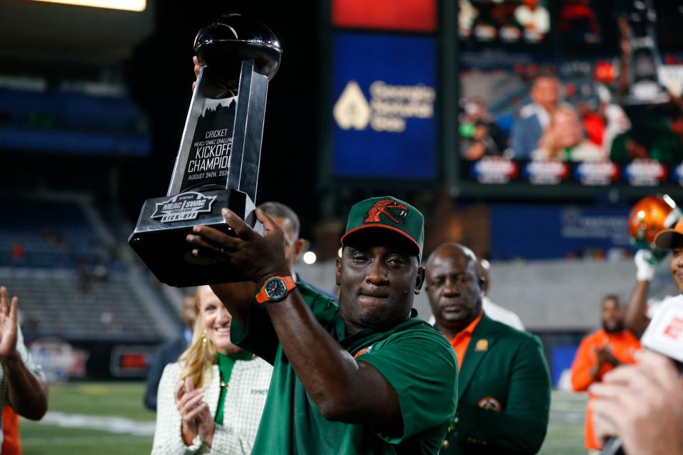 Florida A&M coach James Colzie III raises the game trophy after winning the Cricket MEAC-SWAC Challenge NCAA college football game against Norfolk State in Atlanta on Saturday, Aug. 24, 2024. Florida A&M won 24-23.