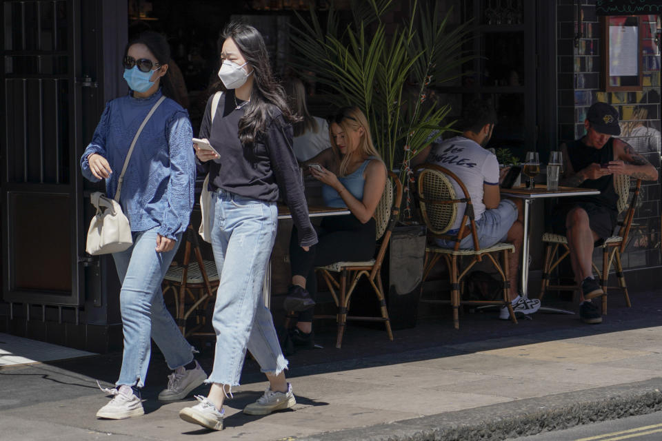 People sit at outdoor tables at a restaurant in Soho, in London, Monday, June 14, 2021. British Prime Minister Boris Johnson is expected to confirm Monday that the next planned relaxation of coronavirus restrictions in England will be delayed as a result of the spread of the delta variant first identified in India. (AP Photo/Alberto Pezzali)