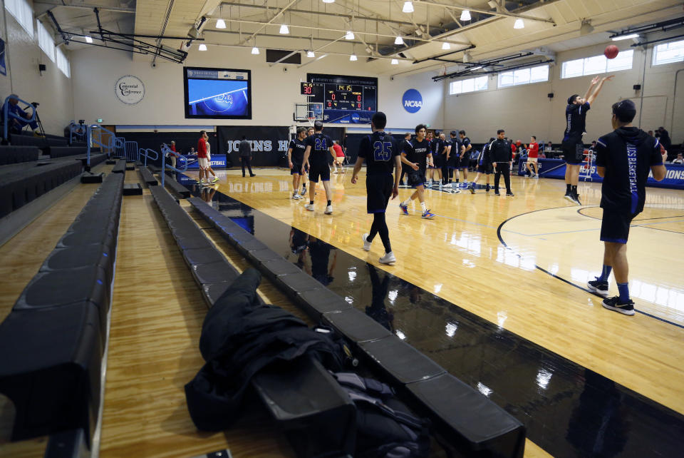 Yeshiva University players, foreground, warm up in a mostly empty Goldfarb Gymnasium at Johns Hopkins University before playing against Worcester Polytechnic Institute in a first-round game at the men's Division III NCAA college basketball tournament, Friday, March 6, 2020, in Baltimore, The university held the tournament without spectators after cases of COVID-19 were confirmed in Maryland. (AP Photo/Jessie Wardarski)