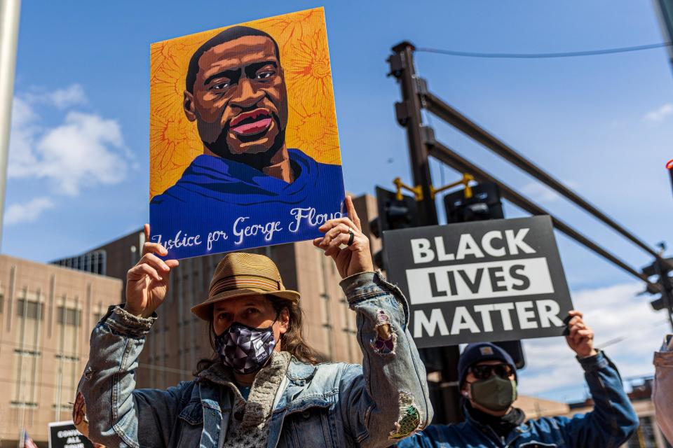 Demonstrators hold signs honoring George Floyd during a protest outside Hennepin County Government Center in Minneapolis on March 28, 2021. / Credit: KEREM YUCEL/AFP via Getty Images