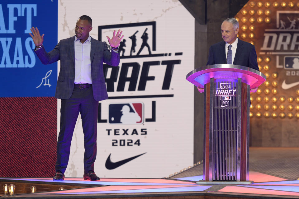 Major League Baseball Commissioner Rob Manfred, at podium, introduces former player Adrián Beltré, left, during the MLB baseball draft in Fort Worth, Texas, Sunday, July 14, 2024. (AP Photo/LM Otero)