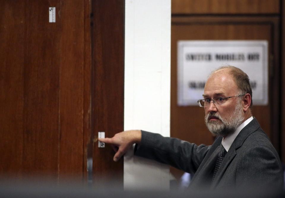 Forensic expert Roger Dixon points at the door through which Reeva Steenkamp was shot, during the trial of Olympic and Paralympic track star Oscar Pistorius at North Gauteng High Court in Pretoria April 15, 2014.The prosecutor in the murder trial of Pistorius ended his five-day cross-examination of the double amputee track star on Tuesday with a stark summary of how he shot his girlfriend, insisting he killed her deliberately after an argument. REUTERS/Siphiwe Sibeko (SOUTH AFRICA - Tags: SPORT ATHLETICS CRIME LAW)