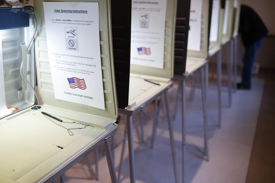 FILE- In this Nov. 8, 2016, file photo a lone voter fills out a ballot alongside a row of empty booths at a polling station in the Terrace Park Community Building on Election Day in Cincinnati. (AP Photo/John Minchillo, File)