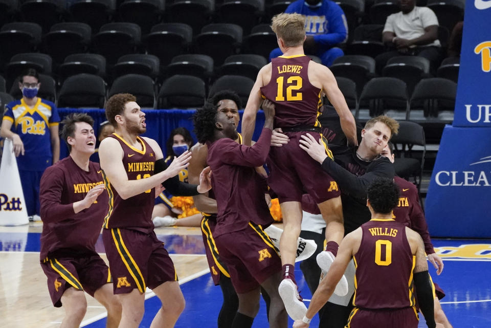 Minnesota's Luke Loewe (12) is hoisted by teammates after Minnesota defeated Pittsburgh 54-53 in an NCAA college basketball game, Tuesday, Nov. 30, 2021, in Pittsburgh. Loewe scored the go-ahead basket in the closing seconds. (AP Photo/Keith Srakocic)