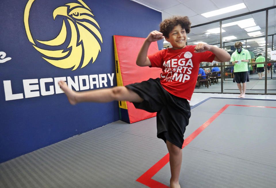 Ty Fenton, 11, smiles as he kicks during martial arts daycare summer camp at Legendary Blackbelt Academy in Richardson, Texas, Tuesday, May 19, 2020. As daycare and youth camps re-open in Texas, operators are following appropriate safety measure to insure kids stay safe from COVID-19. (AP Photo/LM Otero)