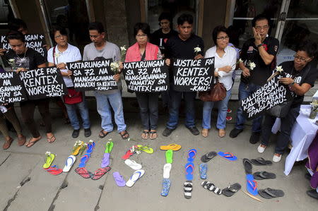 Protesters hold placards calling for a justice for the workers who were killed in a factory, during a mass outside a funeral home in Valenzuela city, north of Manila May 15, 2015. REUTERS/Romeo Ranoco