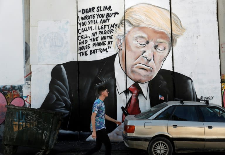 A man walks past a new piece of graffiti depicting US President Donald Trump on the controversial Israeli separation barrier separating the West Bank town of Bethlehem from Jerusalem on October 15, 2017