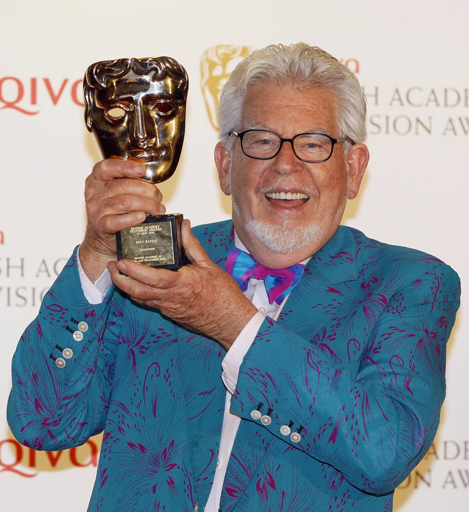 Australian entertainer Rolf Harris holds up the Fellowship Award after winning it at the British Academy Television Awards in London, Sunday, May 27, 2012. (AP Photo/Kirsty Wigglesworth)