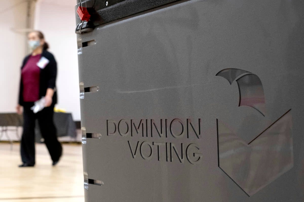 File. A worker passes a Dominion Voting ballot scanner while setting up a polling location at an elementary school in Gwinnett County, Ga., outside of Atlanta, on 4 January 2021 (Associated Press)