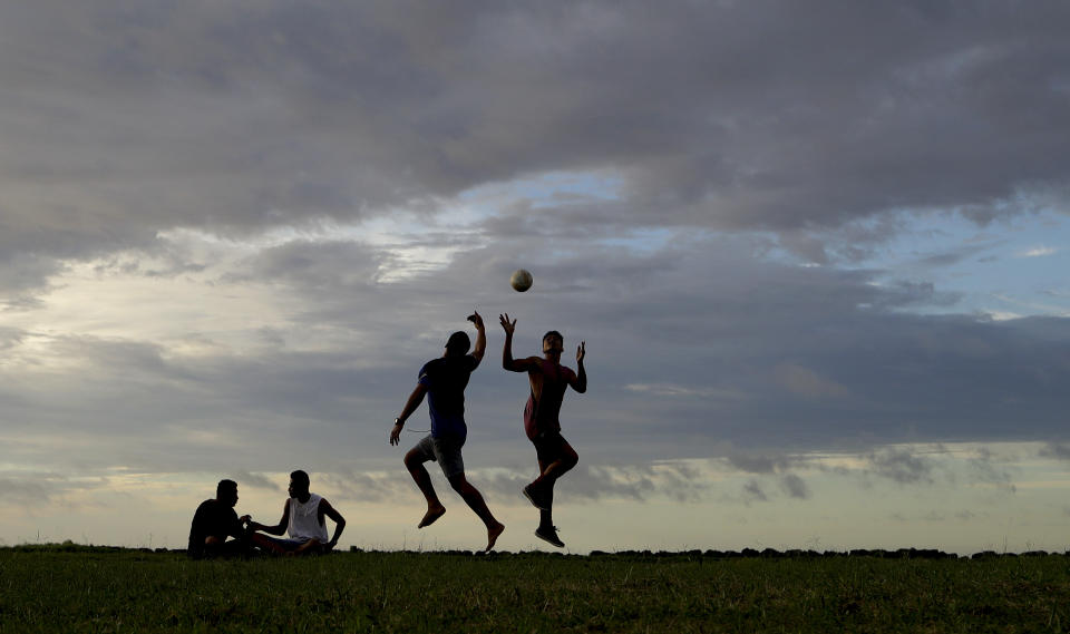 In this Wednesday, April 10, 2019, photo, young men play a game of rugby at sunset in Nuku'alofa, Tonga. China is pouring billions of dollars in aid and low-interest loans into the South Pacific, and even in the far-flung kingdom of Tonga there are signs that a battle for power and influence among much larger nations is heating up and could exact a toll. (AP Photo/Mark Baker)