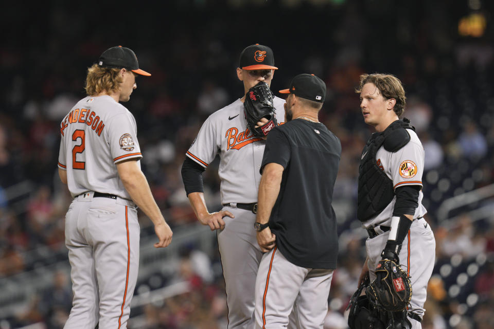 Baltimore Orioles pitching coach Chris Holt, second from right, meets on the mound with third baseman Gunnar Henderson, left, starting pitcher Tyler Wells and catcher Adley Rutschman during the fourth inning of the team's baseball game against the Washington Nationals at Nationals Park, Tuesday, Sept. 14, 2022, in Washington. (AP Photo/Jess Rapfogel)