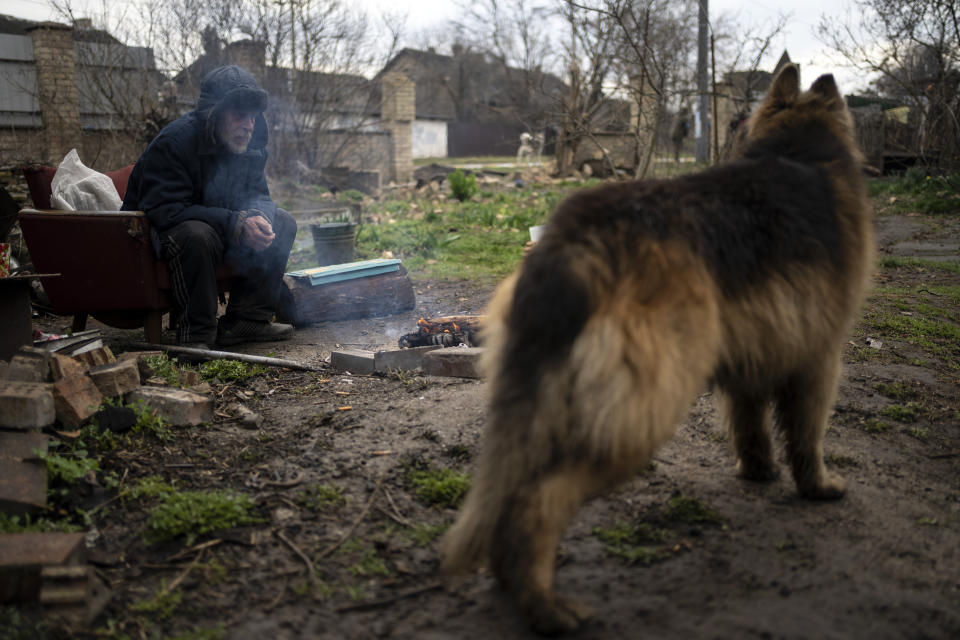 Gregoriev warms himself with a fire in the yard of his house in Bucha, in the outskirts of Kyiv, Ukraine, Saturday, April 9, 2022, which was badly damaged in the war caused by Russia's invasion. (AP Photo/Rodrigo Abd)