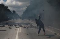 A demonstrator, who opposes the building of a new closed migrant detention centre, throws a rock at riot police during clashes, in the area of Diavolorema on the island of Lesbos