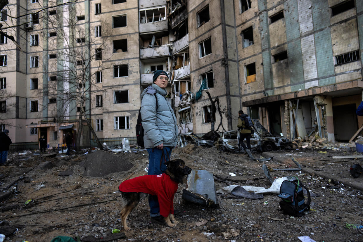 A resident stands with her dog next to a destroyed building after a bombing in Satoya neighborhood in Kyiv, Ukraine, Sunday, March 20, 2022. (AP Photo/Rodrigo Abd)