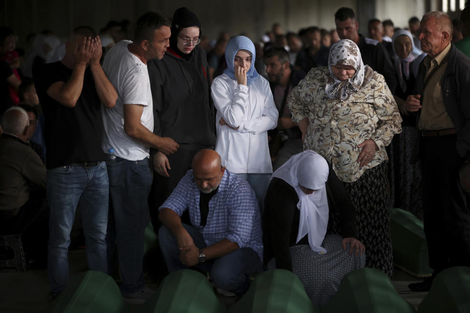 Muslim men and women pray next to the coffins of their relatives, victim of the 1995 Srebrenica genocide in Potocari, Bosnia, Friday, July 8, 2022. The remains of the 50 recently identified victims of Srebrenica massacre, Europe’s only acknowledged genocide since World War II, arrived at the Memorial centre in Potocari where they will be buried on July 11. (AP Photo/Armin Durgut)