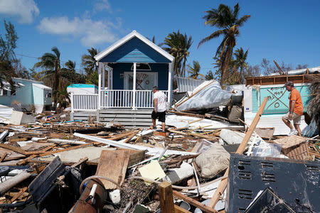 Residents walk though a debris field of former houses following Hurricane Irma in Islamorada, Florida, U.S., September 15, 2017. REUTERS/Carlo Allegri