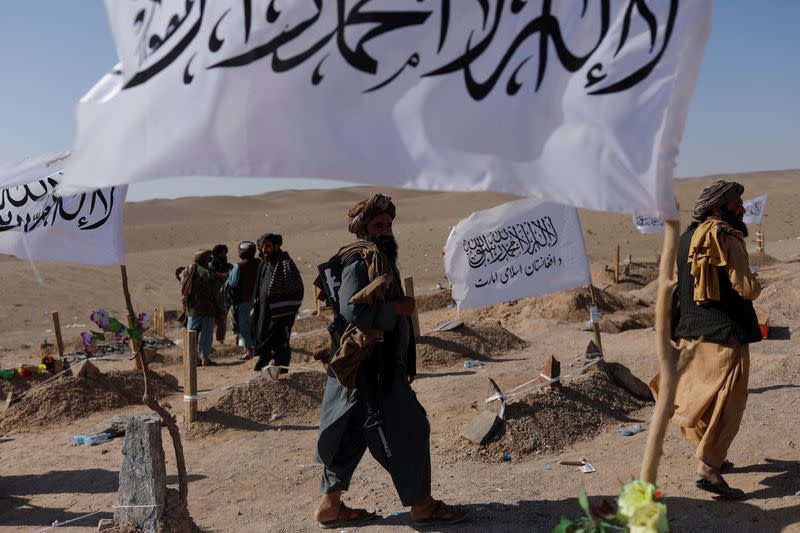 Taliban soldiers walk in a cemetery of victims of the recent earthquake in the district of Zinda Jan, in Herat