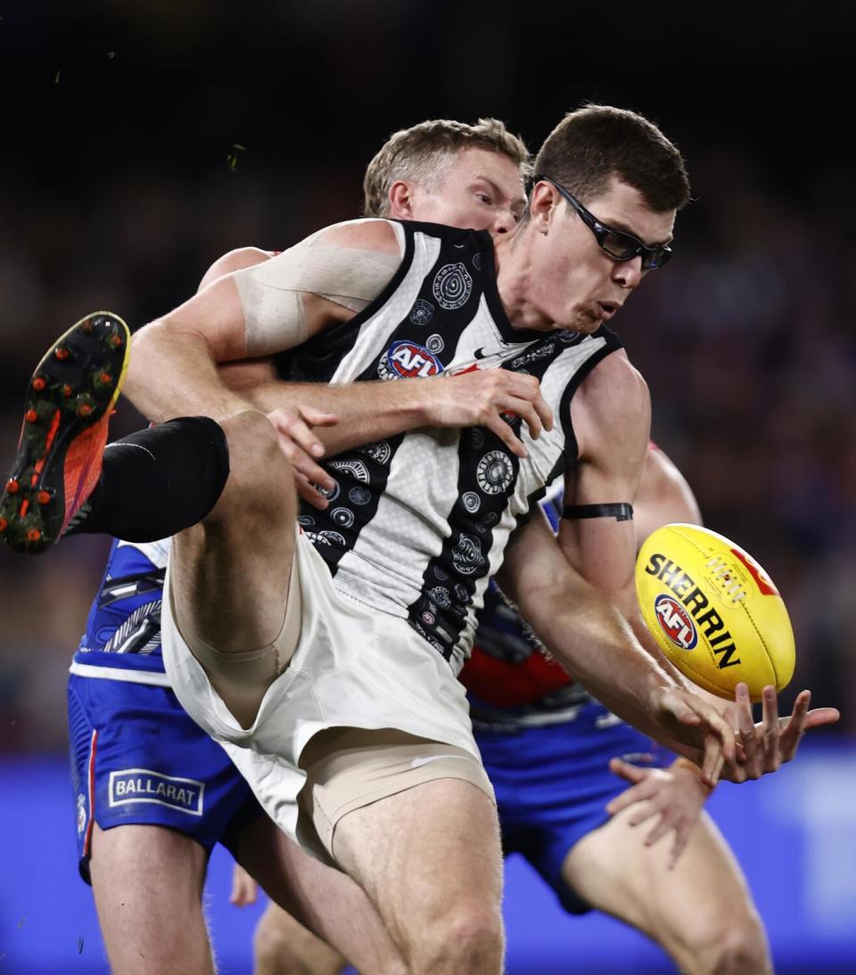 Mason Cox jumps in the air while marking, or grabbing, the ball during an Aussie Rules Football match