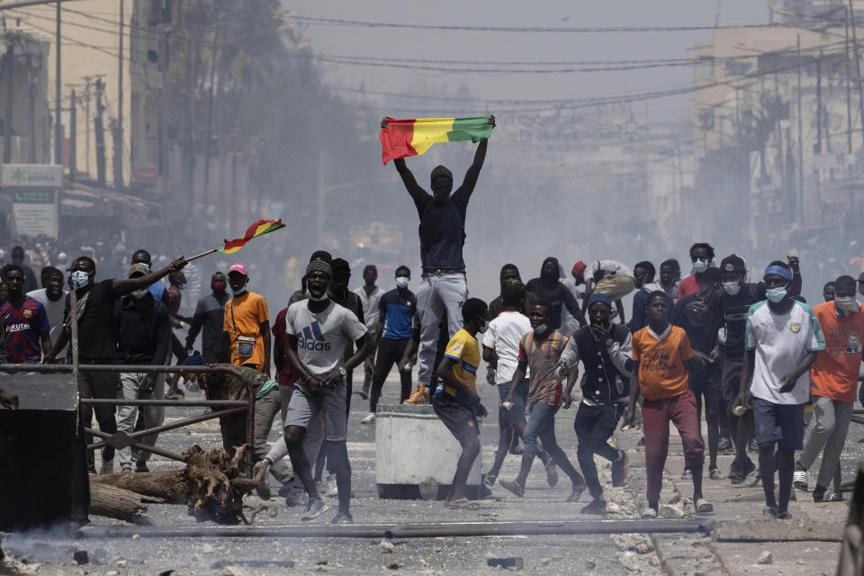 A demonstrator holds up a Senegalese flag during protests against the arrest of opposition leader and former presidential candidate Ousmane Sonko in Dakar, Senegal, Friday, March 5, 2021. Days of violent protests in Senegal have killed at least one person, local reports say, as young people take to the streets nationwide in support of the main opposition leader who was detained Wednesday. (AP Photo/Leo Correa)