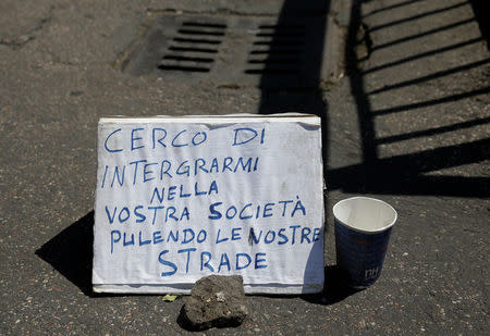 An handwritten banner reading "I'm trying to integrate in your society cleaning our streets" by Christian Okoro of Nigeria is seen in a street in downtown Rome, Italy, May 18, 2017. Picture taken May 18, 2017. REUTERS/Max Rossi