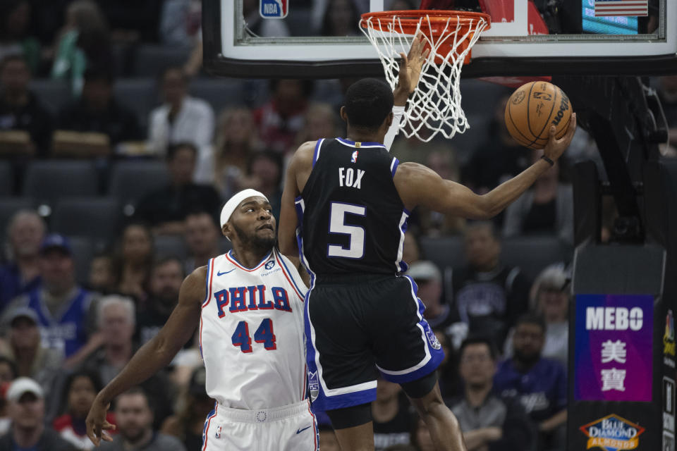 Sacramento Kings guard De'Aaron Fox (5) scores a basket past Philadelphia 76ers forward Paul Reed (44) in the first half of an NBA basketball game in Sacramento, Calif., Monday, March 25, 2024. (AP Photo/José Luis Villegas)