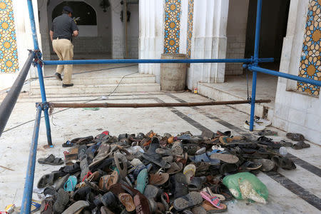 FILE PHOTO - A policeman walks past a pile of shoes left by devotees after Thursday's suicide blast at the tomb of Sufi saint Syed Usman Marwandi, also known as the Lal Shahbaz Qalandar shrine, in Sehwan Sharif, Pakistan's southern Sindh province, February 17, 2017. REUTERS/Akhtar Soomro/File Photo