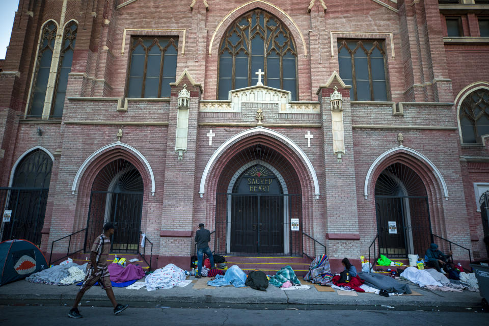 In this photo taken on Tuesday, May 9, 2023, migrants wake up at the campsite outside Sacred Heart Church in downtown El Paso, Texas. As confusion explodes in El Paso, one of the busiest illegal crossings points for migrants seeking to flee poverty and political strife, faith leaders continue to provide shelter, legal advice and prayer. (AP Photo/Andres Leighton)