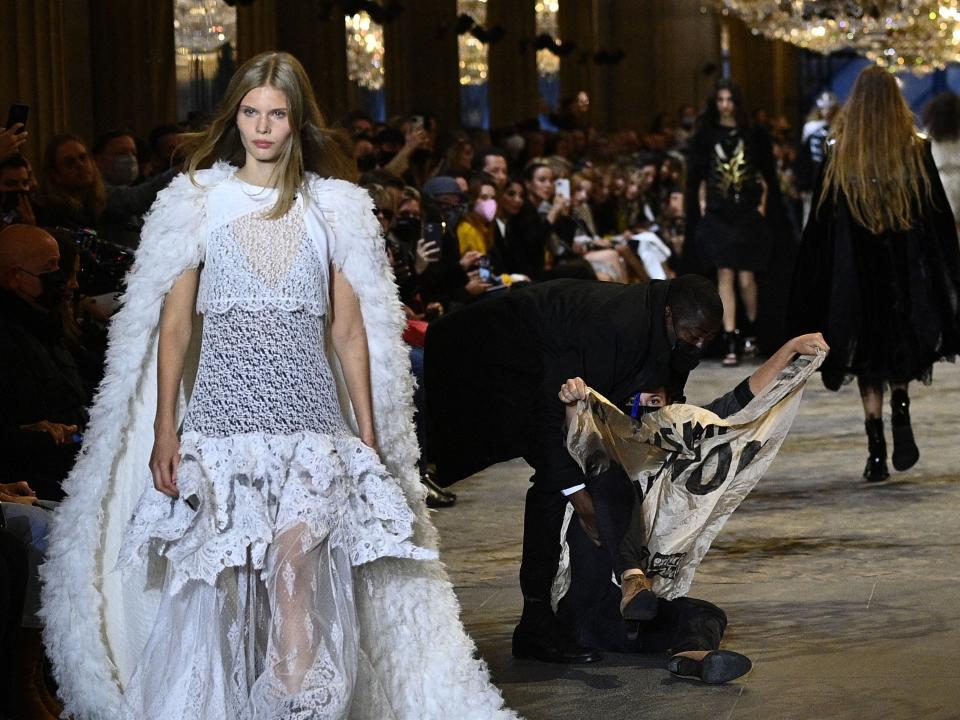 Protester walks down the runway at Louis Vuitton's Paris Fashion Week show.