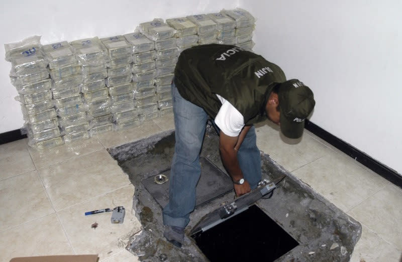 Foto de archivo. Un policía colombiano abre un escondite en el que se encontraron paquetes de billetes de dólares estadounidenses presuntamente del narcotráfico en Cali