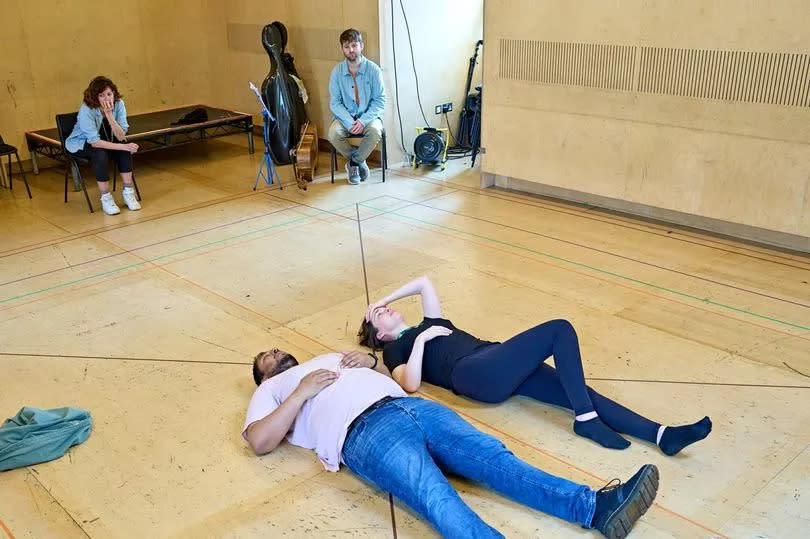 Two people lying on a wood floor on their backs