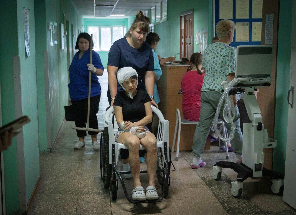 A hospital nurse pushes a wheelchair carrying a woman wounded by the Russian deadly rocket attack at a shopping centre in a city hospital in Kremenchuk in Poltava region, Ukraine, Tuesday, June 28, 2022. 