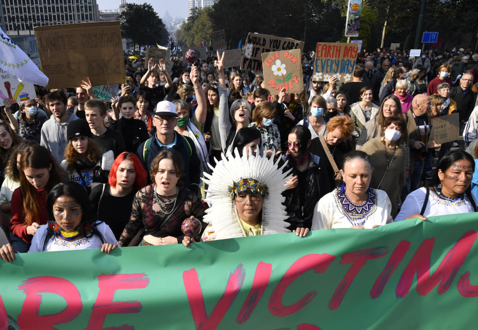 People hold signs and banners as they participate in a climate march and demonstration in Brussels, Sunday, Oct. 10, 2021. Some 80 organizations are joining in a climate march through Brussels to demand change and push politicians to effective action in Glasgow later this month.(AP Photo/Geert Vanden Wijngaert)