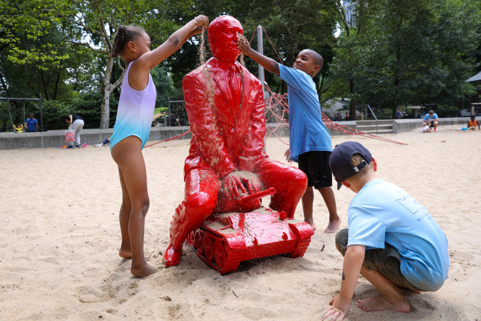 Children put sand on a statue of Russian President Vladimir Putin riding a tank created by French artist James Colomina in Central Park in Manhattan, New York City, U.S., August 2, 2022. / Credit: ANDREW KELLY / REUTERS