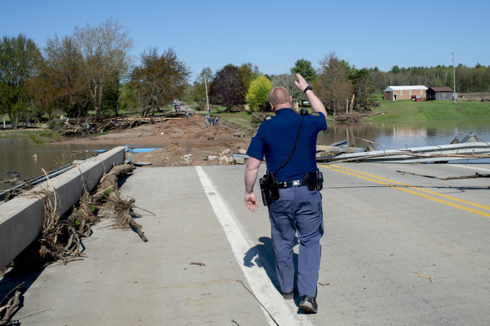 A Michigan State Police trooper waves off residents as they begin to gather to see the ruins of the Curtis Road Bridge on Wednesday, May 20, 2020 in Edenville Township north of Midland. After two days of heavy rain, the Edenville Dam failed and flood waters rushed south, ravaging the landscapre in its path. (Jake May/The Flint Journal, MLive.com via AP)