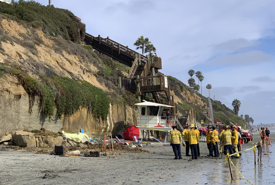 Lifeguards and search and rescue personnel work at the site of a cliff collapse at a popular beach Friday, Aug. 2, 2019, in Encinitas, Calif. At least one person was reportedly killed, and multiple people were injured, when an oceanfront bluff collapsed Friday at Grandview Beach in the Leucadia area of Encinitas, authorities said. (Hayne Palmour/The San Diego Union-Tribune via AP)