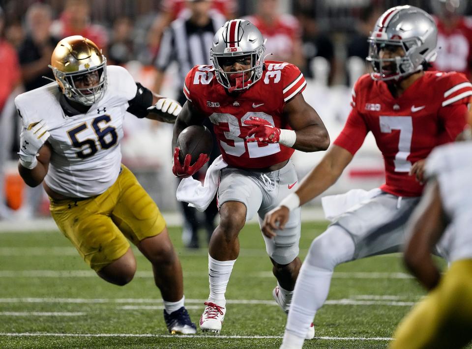 Ohio State running back TreVeyon Henderson (32) carries the ball past Notre Dame  defensive lineman Howard Cross III (56) on a run in the second quarter at Ohio Stadium.