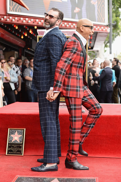 Nicolas Cage and Riko Shibata smiling and holding hands back-to-back on the Hollywood Walk of Fame, with a star plaque on the ground