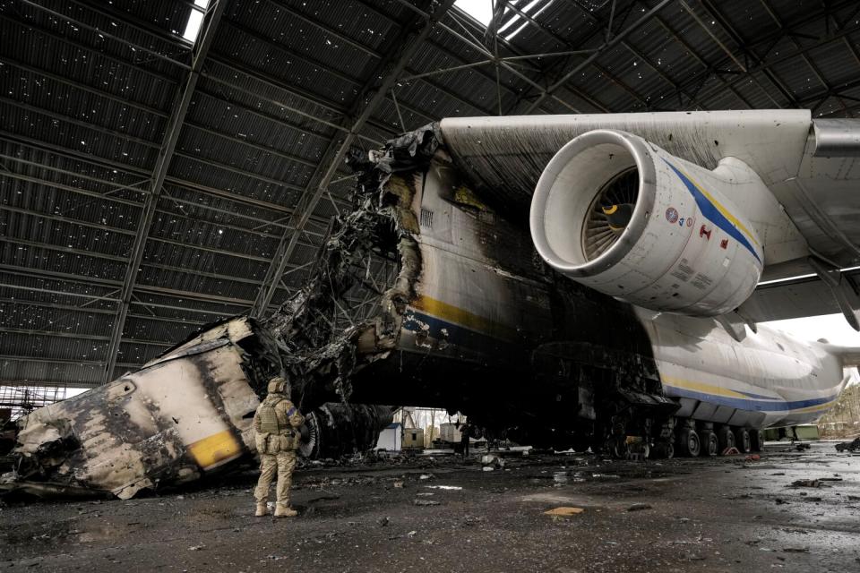 A Ukrainian serviceman walks by the destroyed Antonov An-225 aircraft