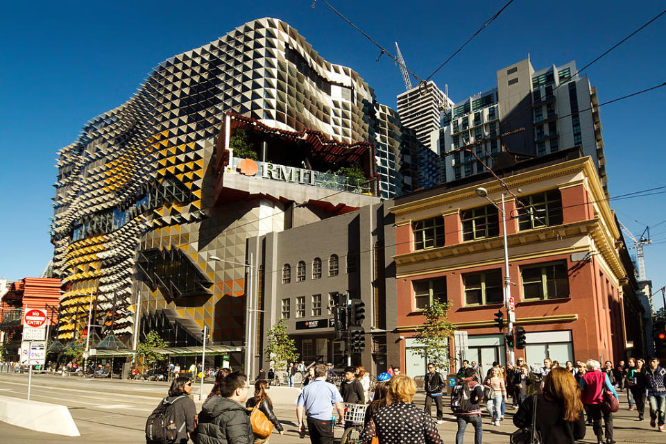 People cross the street in front of an RMIT campus building. 