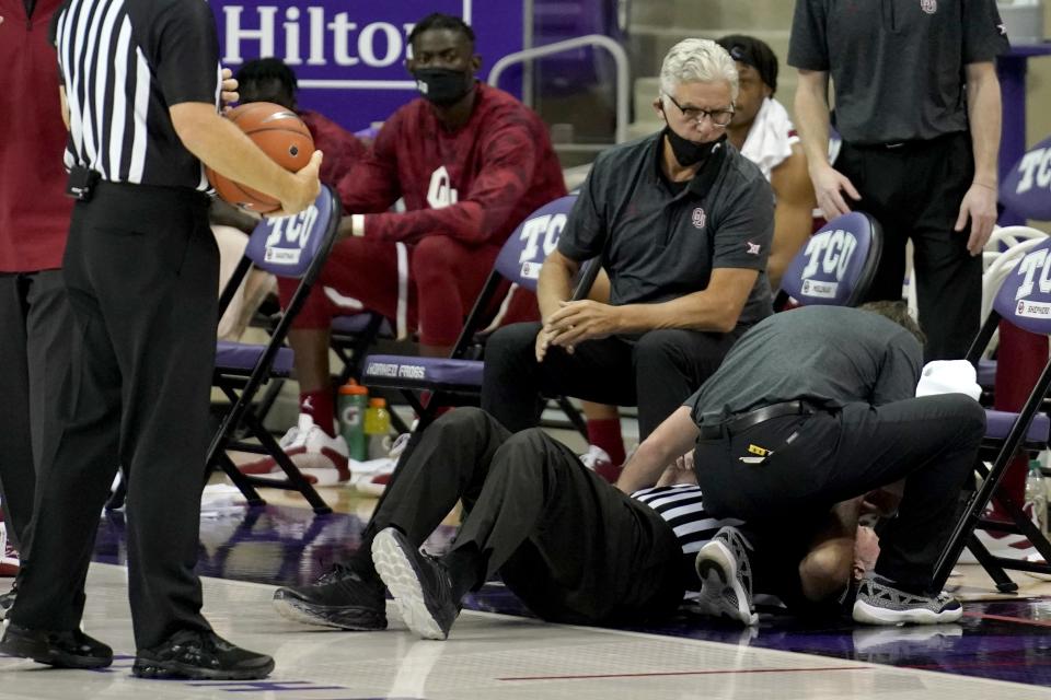 An official receives medical attention after being knocked down in the first half of an NCAA college basketball game between Oklahoma and TCU in Fort Worth, Texas, Sunday, Dec. 6, 2020. The official continued to work the game with a bump and a small cut to the forehead. (AP Photo/Tony Gutierrez)