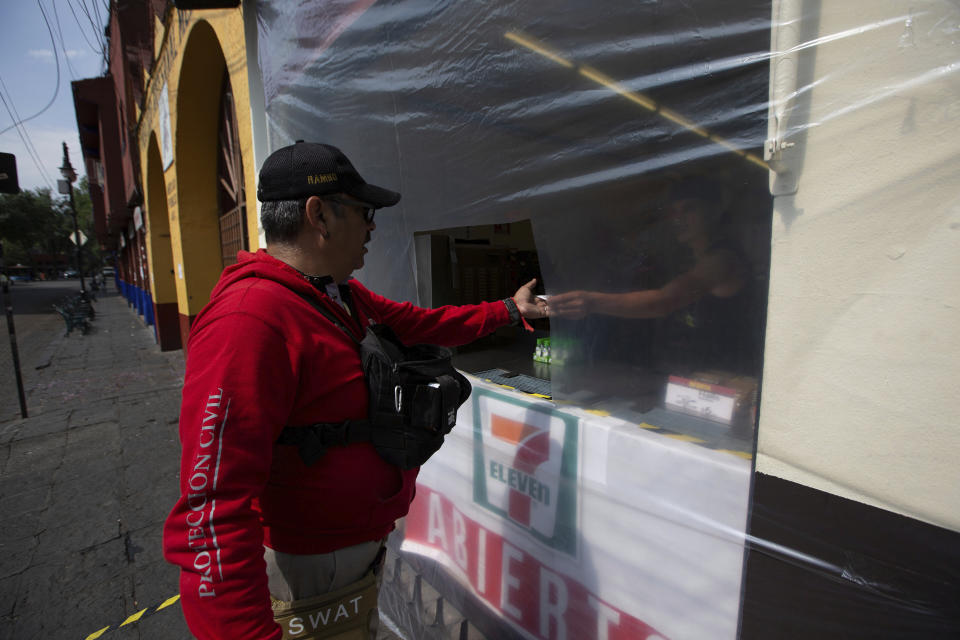 A man pays for a refreshment through a plastic screen, used as a preventive measure against the spread of the new coronavirus, in Mexico City, Saturday, April 4, 2020. Mexico has started taking tougher measures against the new coronavirus, but some experts warn the country is acting too late and testing too little to prevent the type of crisis unfolding across the border in the United States. (AP Photo/Fernando Llano)