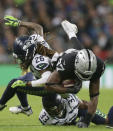 Oakland Raiders tight end Jared Cook (87), center, is tackled by Seattle Seahawks defensive back Tedric Thompson (33), bottom, and cornerback Shaquill Griffin (26) during the first half of an NFL football game at Wembley stadium in London, Sunday, Oct. 14, 2018. (AP Photo/Tim Ireland)