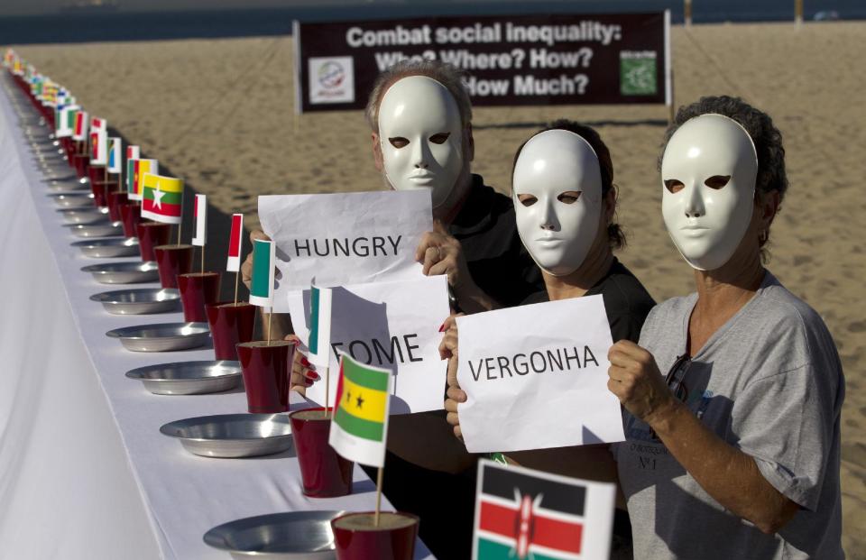 People protest beside a table set with empty plates and national flags as they hold signs that read from right to left in Portuguese; "Shame, hunger" at the Copacabana beach during the United Nations Conference on Sustainable Development, or Rio+20, in Rio de Janeiro, Brazil, Tuesday, June 19, 2012. The Earth summit runs through June 22. (AP Photo/Silvia Izquierdo)