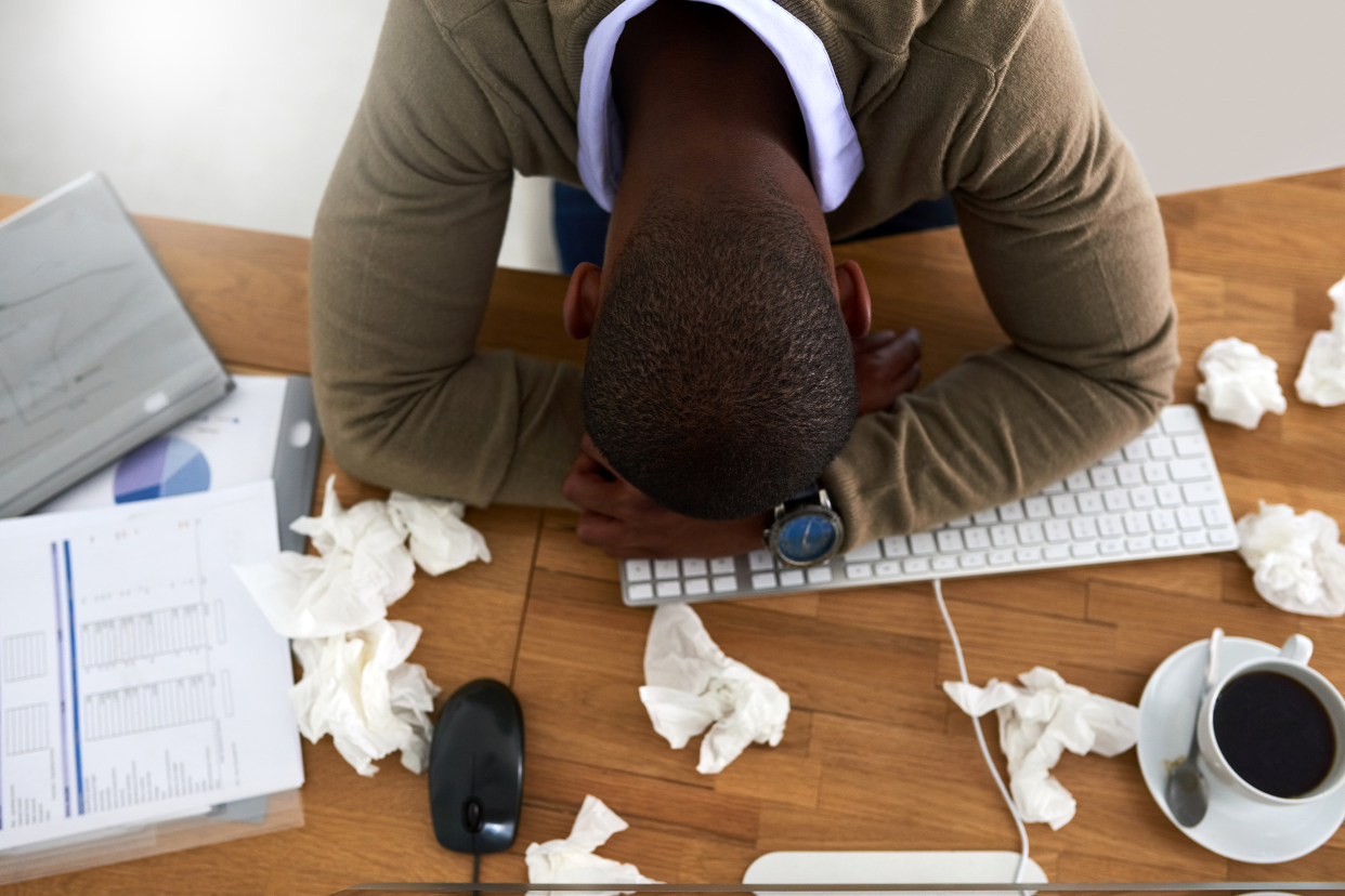 Sick employee with his head on the desk