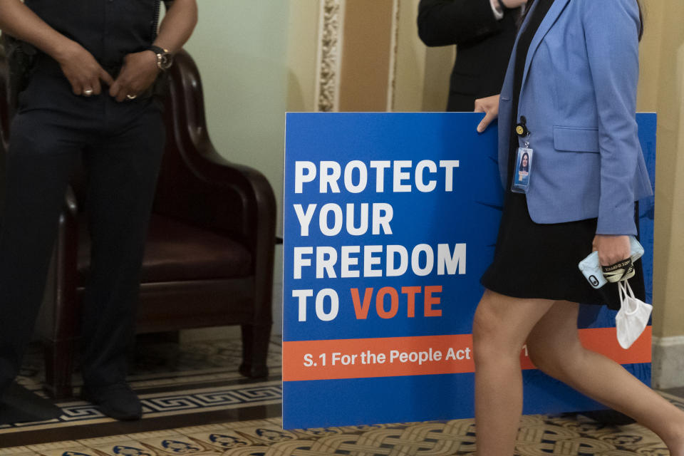 FILE - In this June 22, 2021, file photo, an aide carries a sign to the Senate floor before test vote on the For the People Act, a sweeping bill that would overhaul the election system and voting rights, at the Capitol in Washington. Both parties are bracing for a major legal fight over redistricting. Democrats need court wins more than Republicans because they control the redrawing of political maps in far fewer states than the GOP. (AP Photo/Alex Brandon, File)