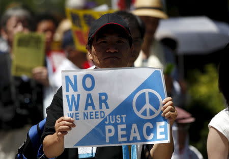 A protester holds a placard during a rally against Japan's Prime Minister Shinzo Abe's administration and his security-related legislation in front of the parliament building in Tokyo July 15, 2015. REUTERS/Issei Kato