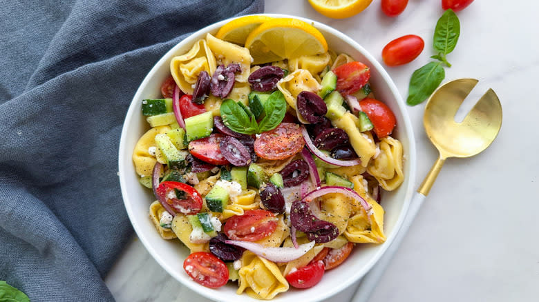 bowl of tortellini Greek salad with gold spoon