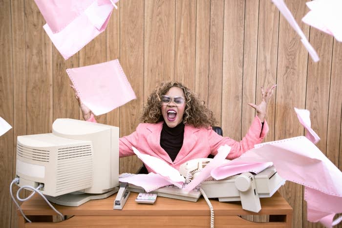 business woman screaming in rage and throwing papers at her desk