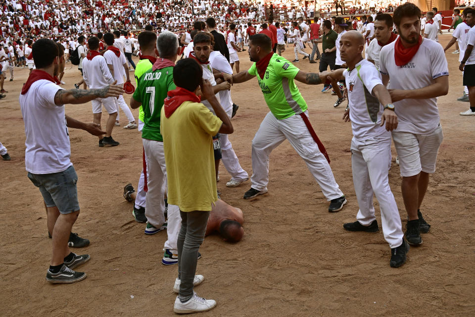 A runner who got hurt when calves were released in the bullring lies on the ground after the running of the bulls at the San Fermin Festival in Pamplona, northern Spain, Tuesday, July 12, 2022. Revellers from around the world flock to Pamplona every year for nine days of uninterrupted partying in Pamplona's famed running of the bulls festival which was suspended for the past two years because of the coronavirus pandemic. (AP Photo/Alvaro Barrientos)