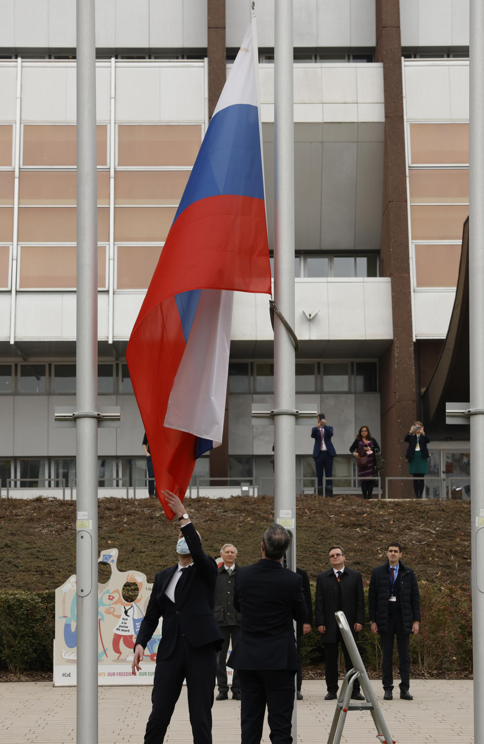 Employees of the Council of Europe remove the Russian flag from the Council of Europe building, Wednesday, March 16, 2022 in Strasbourg. The Council of Europe expelled Russia from the continent's foremost human rights body in an unprecedented move over its invasion and war in Ukraine. The 47-nation organization's committee of ministers said in statement that "the Russian Federation ceases to be a member of the Council of Europe as from today, after 26 years of membership." (AP Photo/Jean-Francois Badias)